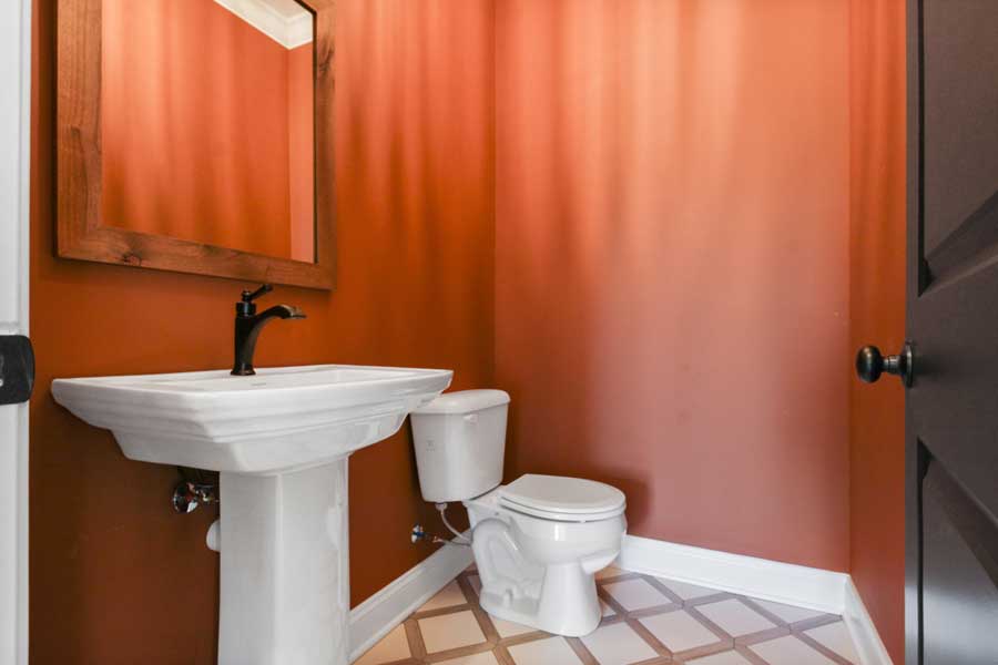half bathroom with white toilet and burnt orange walls