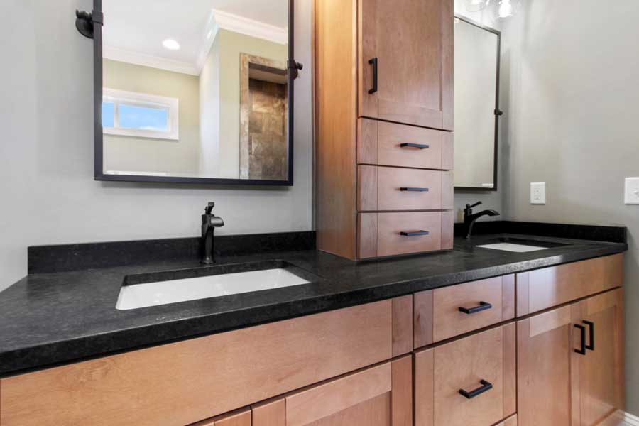 double vanity sinks with wood cabinets and black granite countertops