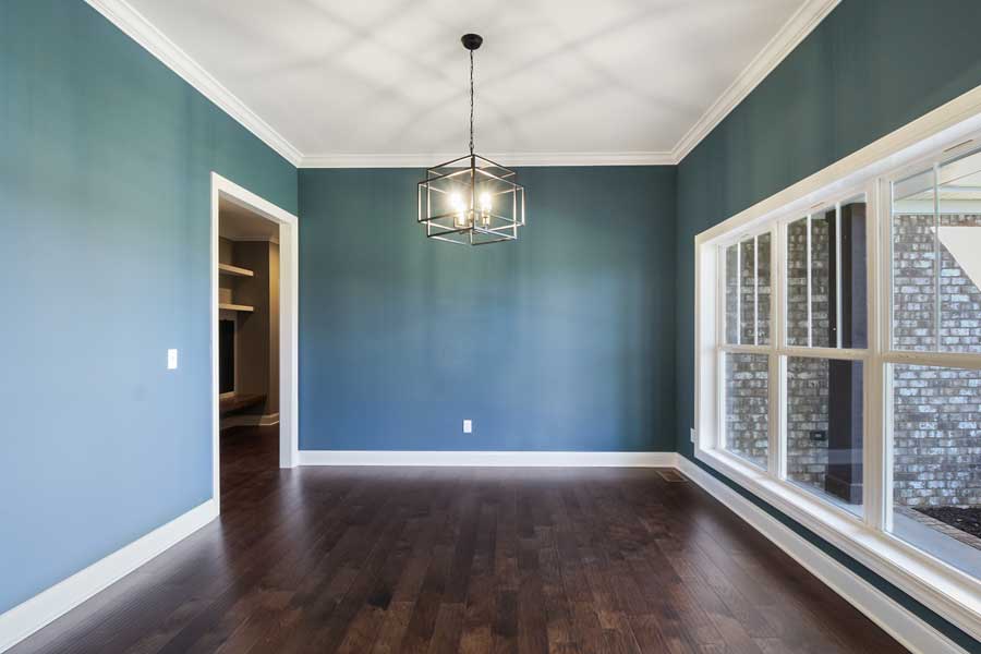 blue room with wood flooring and a lot of natural light from three windows.