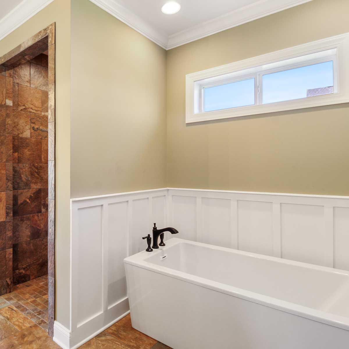 white bathtub with white trim in a tan bathroom